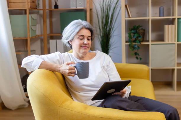 istock Senior woman relaxing on sofa, enjoying coffee and using digital tablet at home 2200876096
