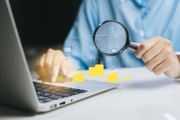 istock Person Using Magnifying Glass to Examine Digital Data on Laptop 2200879366