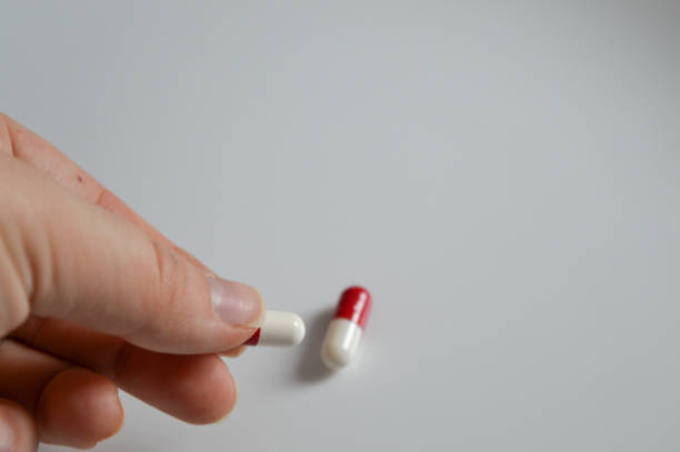 istock red and white capsules on a white surface with a hand reaching for ones medical pharmaceutical drugs self-medication medication adherence responsible drug use overdose awareness mental health 2200890588