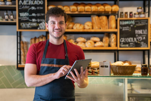 istock Happy waiter at a bakery and holding a digital tablet 2200892646