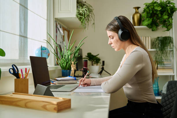 istock Young woman student studying writing in notebook using laptop, at home 2200894826