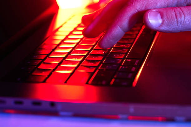 istock Finger touching keyboard under colorful lighting during late-night work session 2200895022