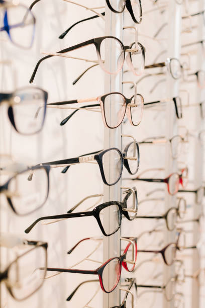 istock Customer chooses eyeglasses with clear lenses from the shelf. Eyesight correction. Stand of eyeglasses with different frames in the optical store. 2200897972