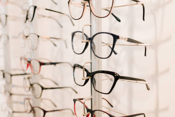 istock Eyesight correction. Stand of eyeglasses with different frames in the optical store. Customer chooses eyeglasses with clear lenses from the shelf. 2200898109