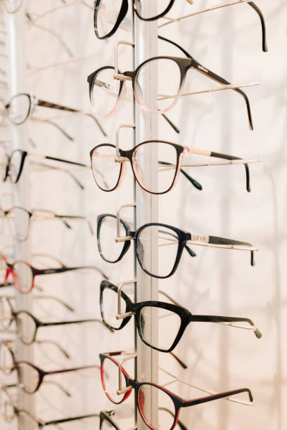 istock Eyesight correction. Stand of eyeglasses with different frames in the optical store. Customer chooses eyeglasses with clear lenses from the shelf. 2200898110