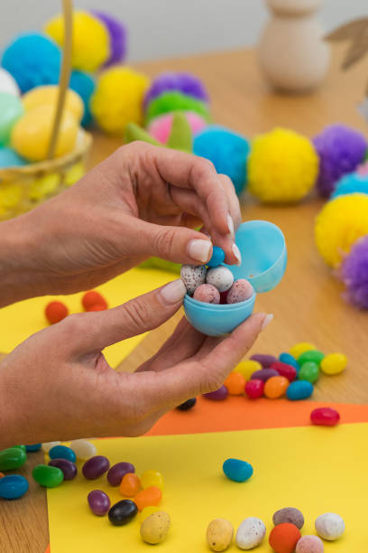 istock A woman fills plastic Easter eggs with egg-shaped candies. Egg hunt concept. Happy Easter 2200899472