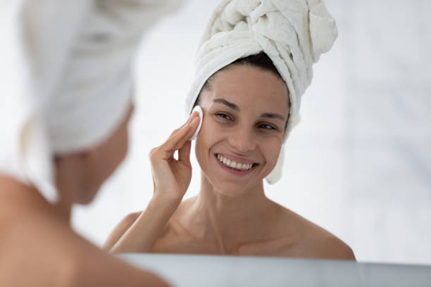 istock Smiling girl clean face using cotton sponge in bath 2200904837