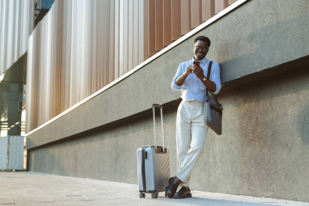 istock Young professional man with luggage texting outdoors in urban environment 2200905037