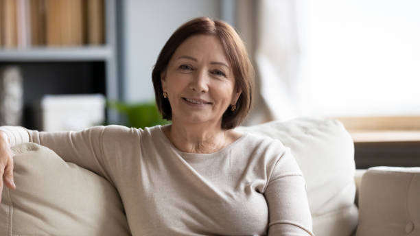 istock Smiling middle-aged woman sitting on couch looking at camera 2200906271