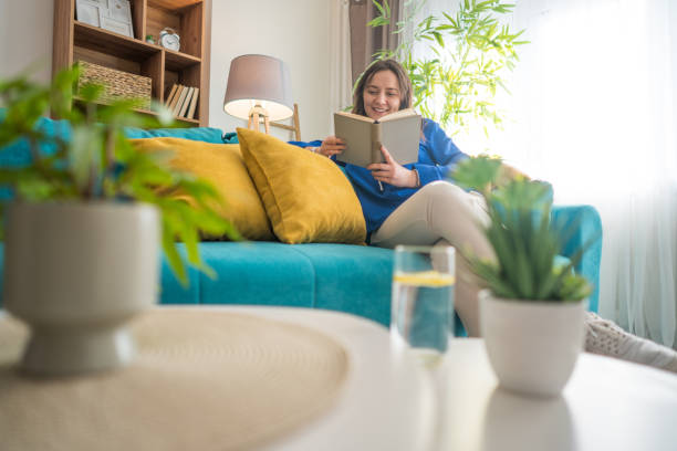 istock A woman sits on her favorite sofa, enjoying a peaceful moment while reading a book 2200906992