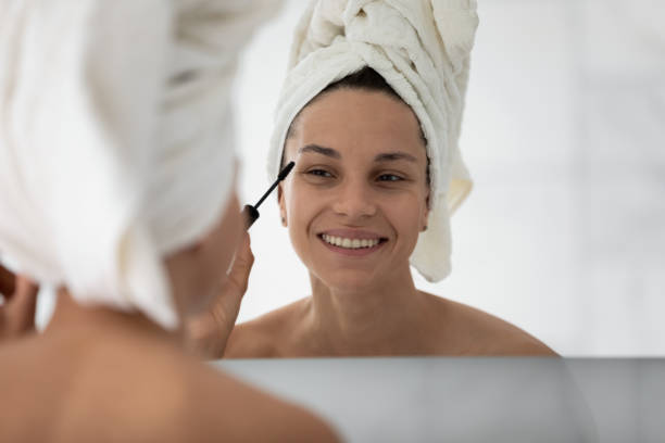 istock Smiling girl look in mirror paint lashes in bath 2200907646