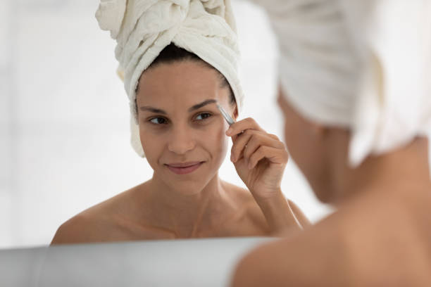 istock Young woman look in mirror pinch eyebrows in bathroom 2200908488