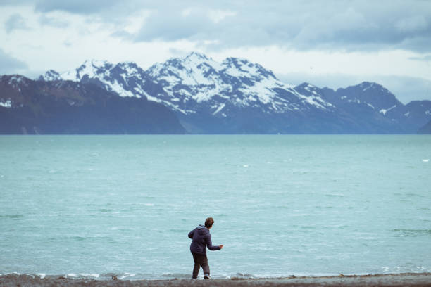 Teenage boy stone skimming on Resurrection bay Alaska.