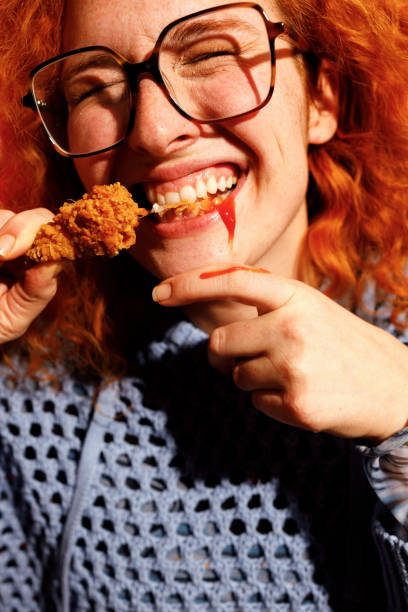 istock Redhead Woman Enjoying Spicy Fried Chicken 2200910931