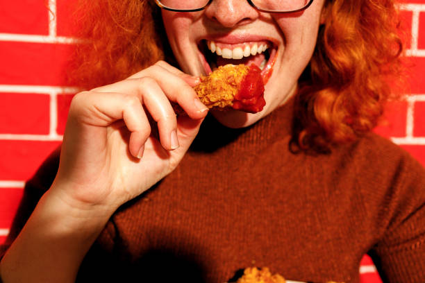 istock Redhead Woman Enjoying Spicy Fried Chicken 2200910954