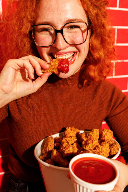 istock Redhead Woman Enjoying Spicy Fried Chicken 2200910960