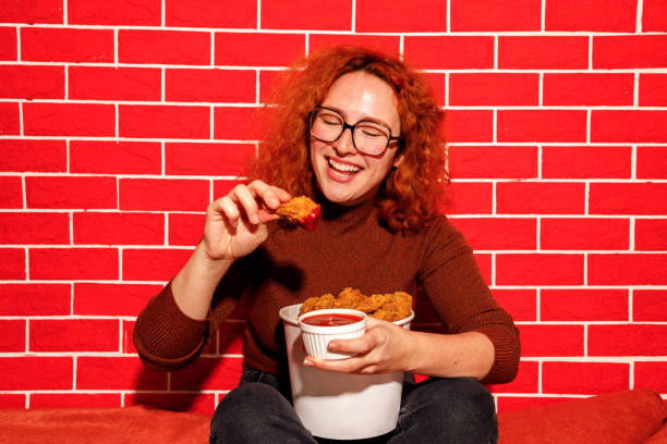 istock Redhead Woman Enjoying Spicy Fried Chicken 2200910962