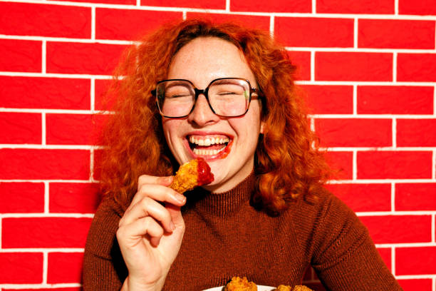 istock Redhead Woman Enjoying Spicy Fried Chicken 2200910963