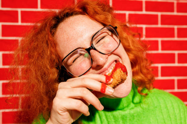 istock Redhead Woman Enjoying Spicy Fried Chicken 2200910978