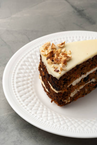 istock Delicious layered cake topped with cream and nuts placed on a white decorative plate 2200911312