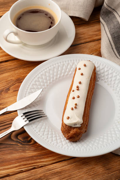 Enjoying a delicious eclair with coffee on a cozy wooden table during a relaxed afternoon
