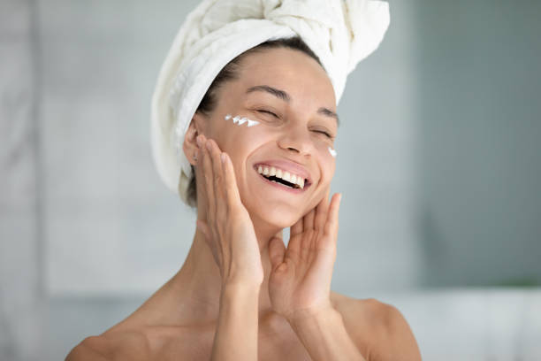 istock Overjoyed young woman use face cream in bathroom 2200920481