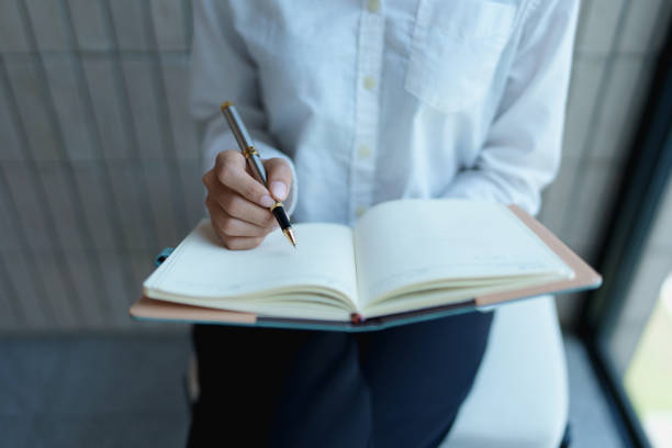 istock Individual writing in notebook with pen in modern office environment, focused on creative and productive work 2200921553
