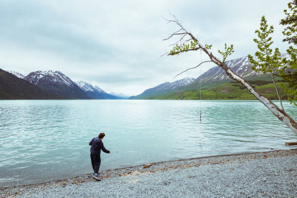 Teenage boy stone skimming on Resurrection bay Alaska.