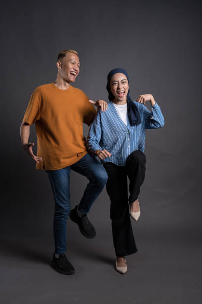 istock Two cheerful young adults pose playfully in casual attire against a grey background, expressing joy and friendship 2200950849