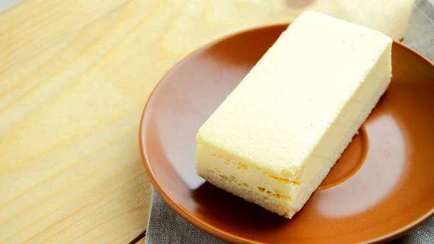 istock Laying out a brown plate with a rectangular slice of delicious cheesecake close-up on the table 2200954024