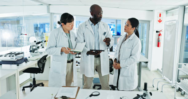 istock Scientist, team and discussion for research, notes and experiment results or medical information. People, notebook and laboratory technician with documents for virus development or pathology test 2200954101