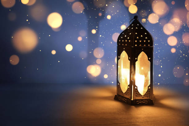 istock Ornamental dark Moroccan, Arabic lantern on table burning at night. Glittering bokeh lights. Greeting card for Muslim community holy month Ramadan Kareem, Eid Mubarak. Festive background. 2200954456