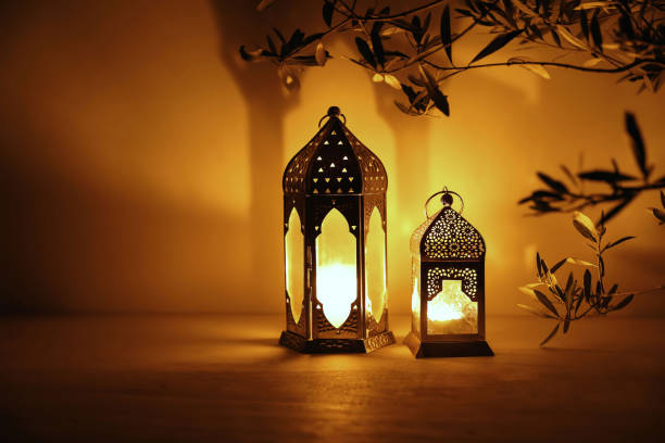 istock Two Moroccan lanterns on table at nigh. Blurred olive tree branches. Golden glow. Festive banner, invitation for Muslim holiday Ramadan Kareem. Eid mubarak celebration. Religion concept, copy space. 2200954464