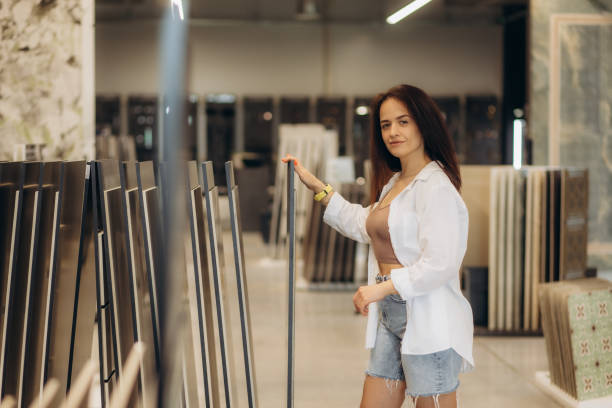 istock Happy brunette female interior designer choosing flooring tile color texture samples at store shop. Woman architect choice floor and wall finishing material for architecture and construction industry. 2200957751