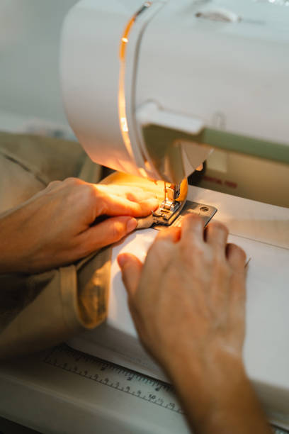 istock Close-up of woman hands using seam ripper tool to unstitch the thread while sewing beige fabric with sewing machine 2200961181