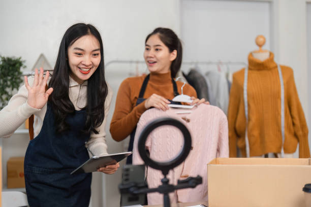 istock Excited women presenting fashion items for online sales, emphasizing creativity and teamwork. 2200961866