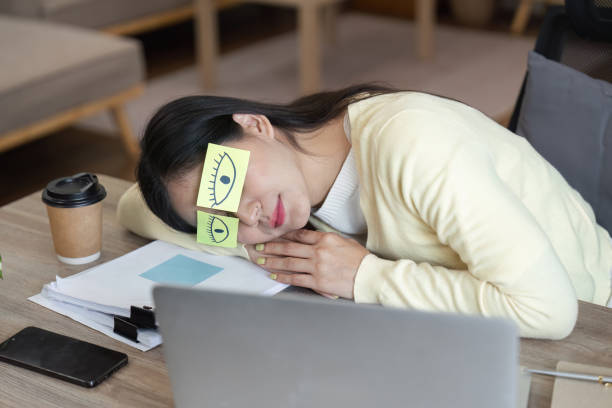 istock Woman in home office daydreaming with sticky notes on her forehead, representing the struggle of staying focused while working remotely. 2200963199