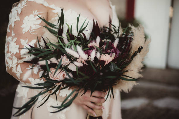 Dried bouquet of wedding flowers Plus sized bride in long sleeved lace wedding dress holding bouquet of dried boho flowers plus size boho clothing stock pictures, royalty-free photos & images