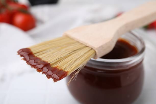 istock Marinade in jar and basting brush on white table, closeup 2200966865