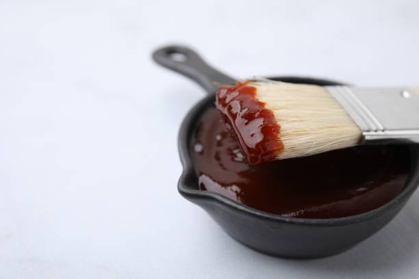 istock Marinade in gravy boat and basting brush on white table, closeup. Space for text 2200966922