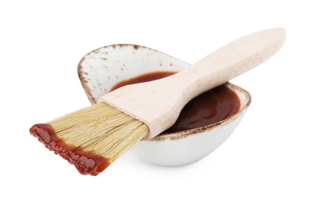 Marinade in gravy boat and basting brush isolated on white