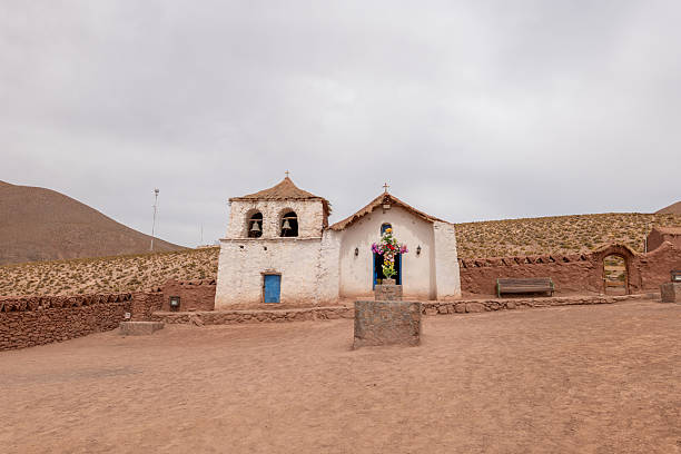Historic stone church with vibrant floral display in dry terrain. Iconic architecture showcasing cultural heritage. Scenic desert backdrop with rustic charm.