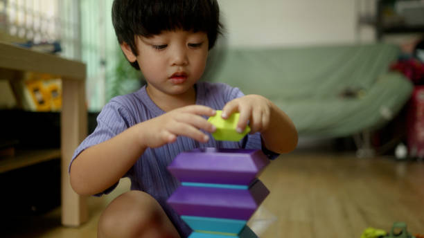 istock Asian boy playing with wooden blocks learning organizing shapes using brain and hands. 2200973104