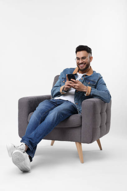 istock Happy man using smartphone in armchair on white background 2200975277