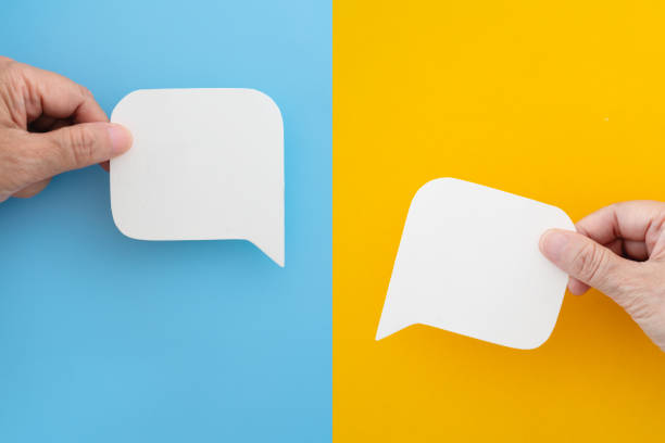 istock For conceptual image about communication and social media, FAQ, customer feedback, hand hold real blank white  speech bubble paper cut on blue and yellow background 2200979063