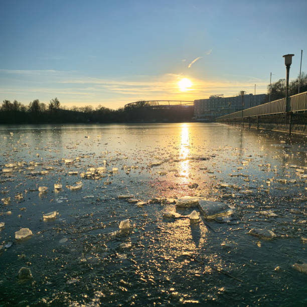 An incredibly tranquil evening scene that features a stunning sunset reflecting beautifully on icy water Hanover Maschsee