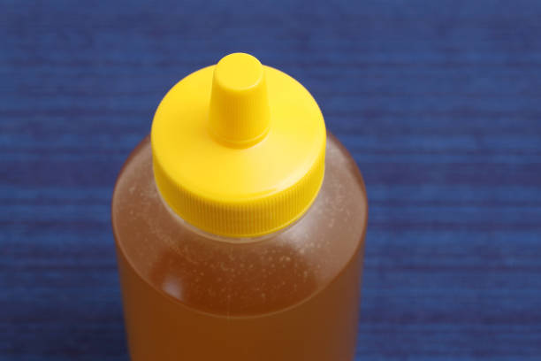 Plastic bottle of honey on table background