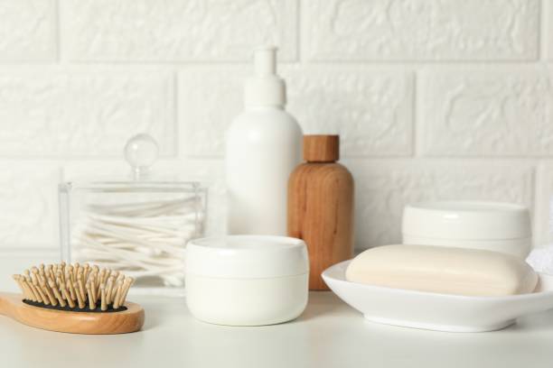 istock Different bath accessories and personal care products on white table near brick wall 2200986522