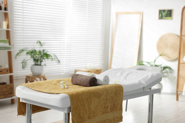 istock Massage table with towels and flowers in spa center 2200986593