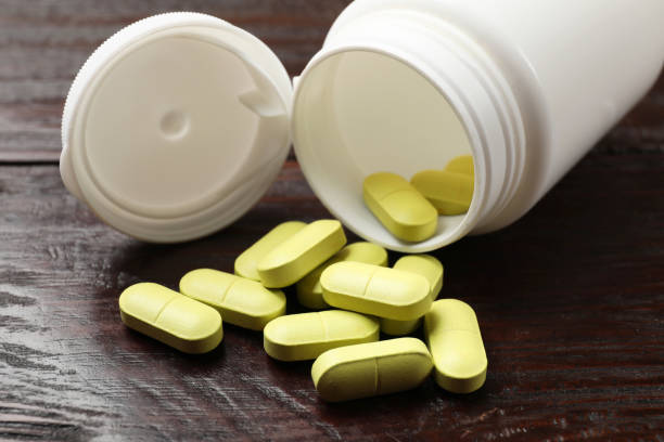 istock Bottle and vitamin pills on wooden table, closeup 2200986627